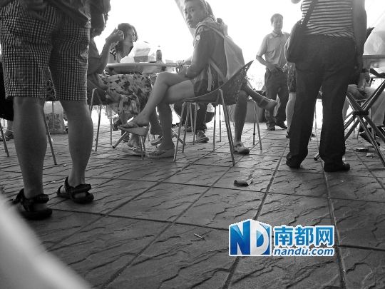 泰国一景区购物点外，中国游客围在一起等候，现场闹哄哄，地上散落着包装纸、烟头等杂物。